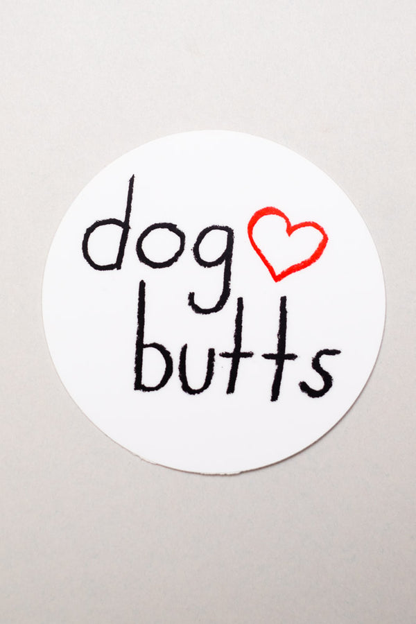 A round white sticker with black text that reads "dog butts" and an outline of a red heart. Background is white.