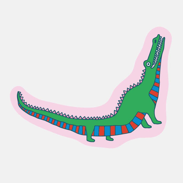 Die cut sticker of a green alligator  with a striped red and blue underside against a pink background.