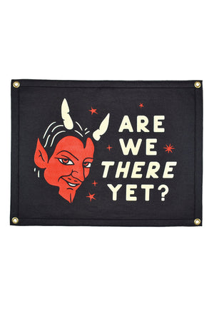 A rectangular felt flag with an illustrated depiction of the devil with the text "are we there yet?"