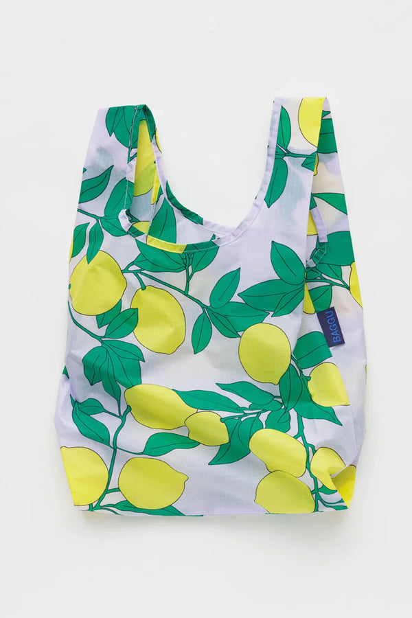 Small reusable tote featuring yellow lemons and green leaves all of it. White background.