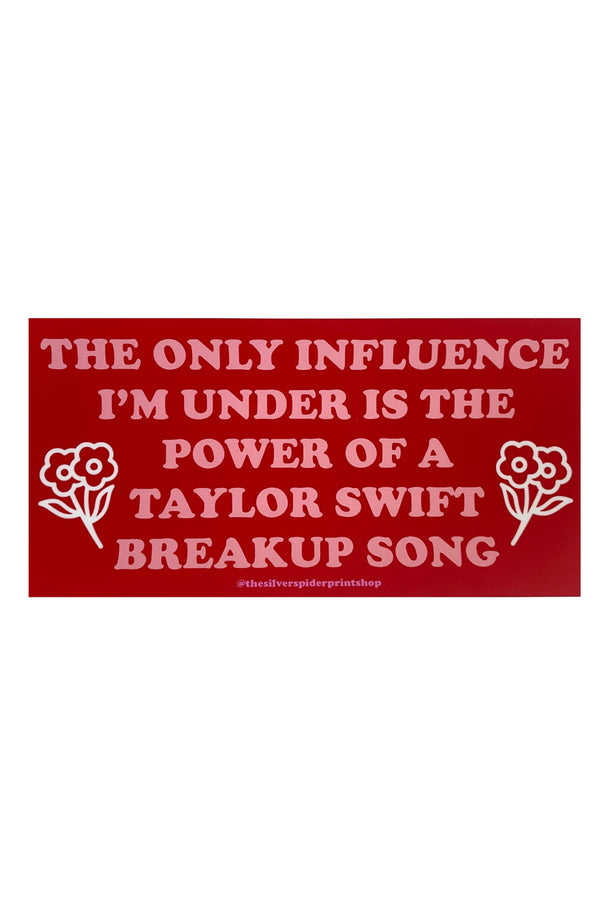 Red Bumper sticker on a white background. The bumper sticker says "The only influence I'm under is the power of a Taylor Swift breakup song" with small flowers on both sides of the text. 