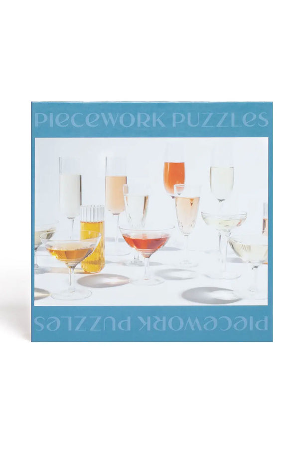 The back of a teal blue jigsaw puzzle box. The puzzle is called "Champagne Problems" and has a large photo of several glasses of champagne arranged on a table.