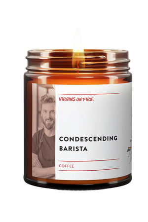 Amber glass candle jar. The candle features a white label that says Condescending Barista and features a black and white photo of a man in an apron. The brand is Virgins on Fire. White background.