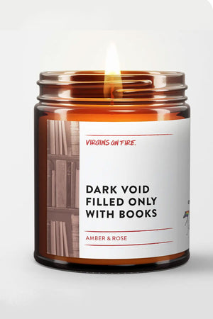 Amber glass jar with white label. The label says Dark Void Filled Only with Books. Scent is Amber Rose. The label also features a black and white photo of books on a bookshelf. White background.