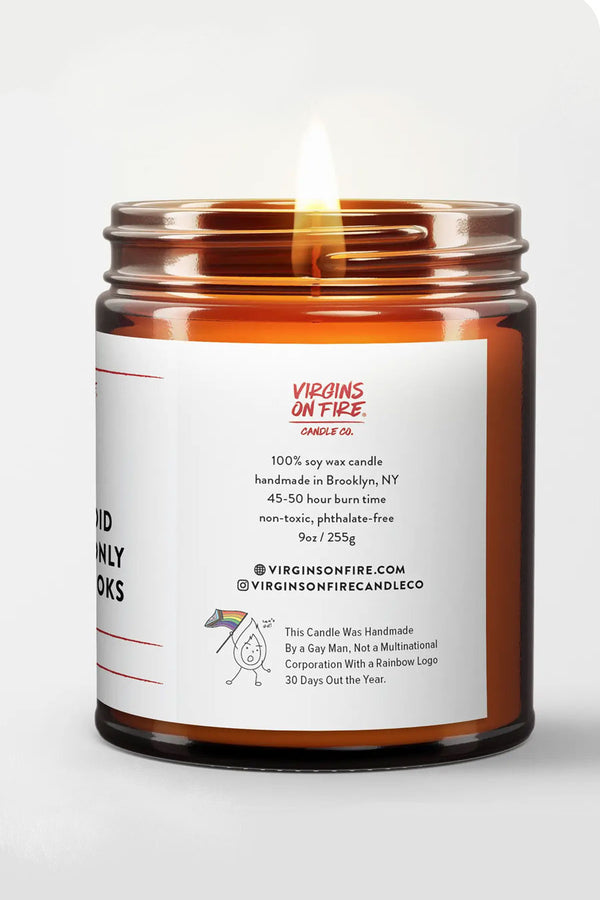 Amber Glass Candle Jar with a white label. The label says Virgins on Fire Candle Co. This candle was handmade by a gay man, not a multinational corporation with a rainbow logo 30 days out of the Year. White background.