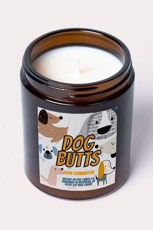 Amber glass candle jar. The label says Dog Butts in yellow lettering. Around the lettering are 6 illustrations of dogs. White background.
