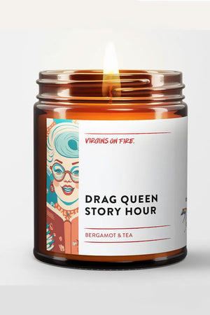 Amber Glass candle jar with white label. The label says Drag Queen Story Hour. Scent is Bergamot and Tea. The label also features a blue and pink illustration of a drag queen reading a book.