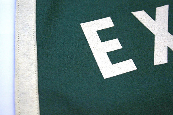 A close up view of a forest green and white felt flag's stitching.