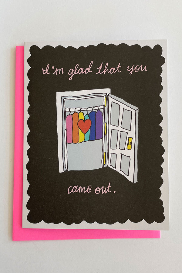 A greeting card with a black background and the illustrated image of an open closet door with rainbow colored clothing on the inside. The text of the card reads "I'm so glad you came out."