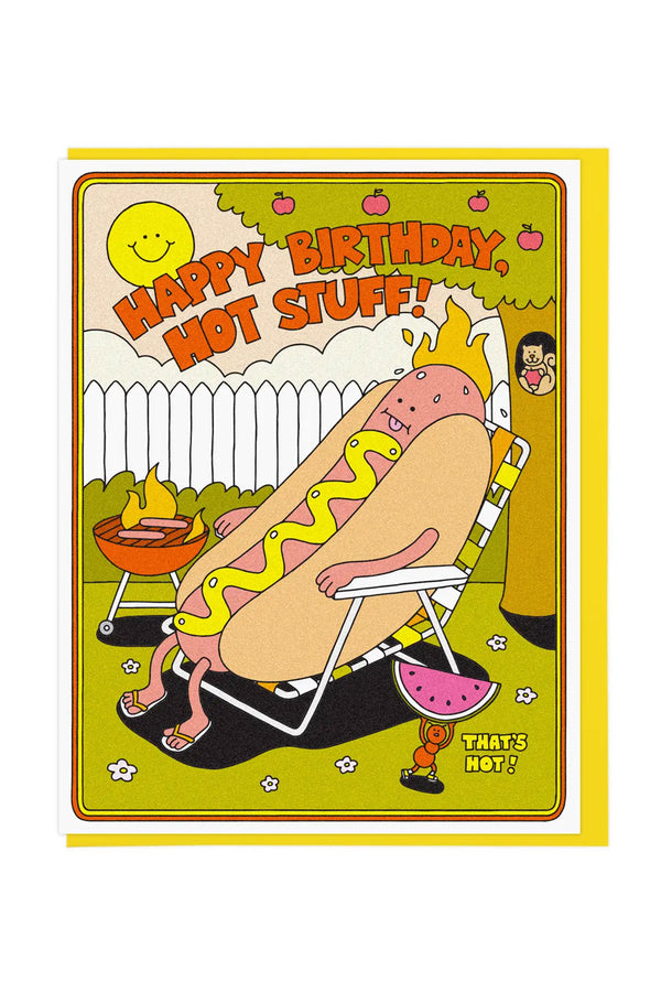 White card with a yellow envelope on a white background. The card features a hotdog character sitting in the sun with mustard and wearing flip flops. He is sitting next to a bbq grill that is on fire. There is an Ant character in the bottom right running away from the scene with a slice of watermelon. The Ant expresses in yellow text "Thats Hot!" The hot Dog is next to an apple tree that has a hole in the trunk, revealing a happy squirrel holding an apple.