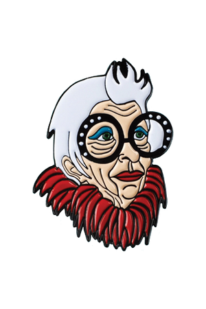 A die cut lapel pin of the likeness of fashion icon, Iris Apfel, an older white haired woman with large bejeweled black rimmed glasses and a red feather boa.