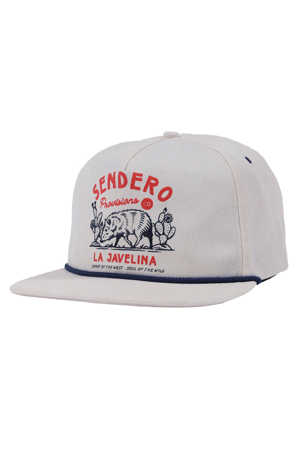 A white flat-brimmed hat with navy trim by the bill. The orange-red text reads "Sendero Provisions, La Javelina" and has an illustrat ion of a javelina near cacti in navy ink.