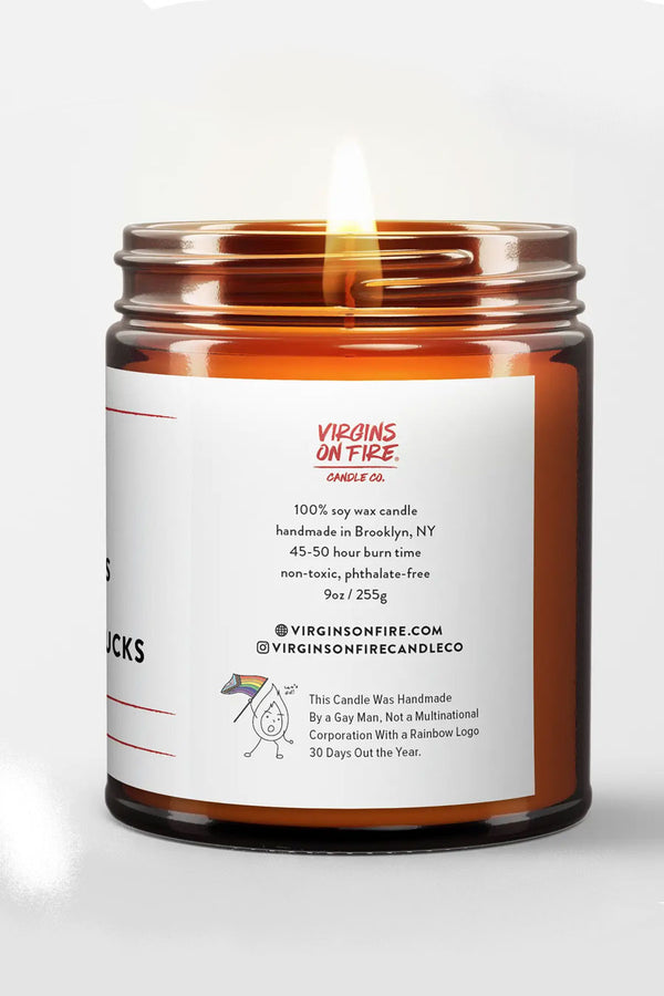 Amber Glass Candle Jar with a white label. The label says Virgins on Fire Candle Co. This candle was handmade by a gay man, not a multinational corporation with a rainbow logo 30 days out of the Year. White background.