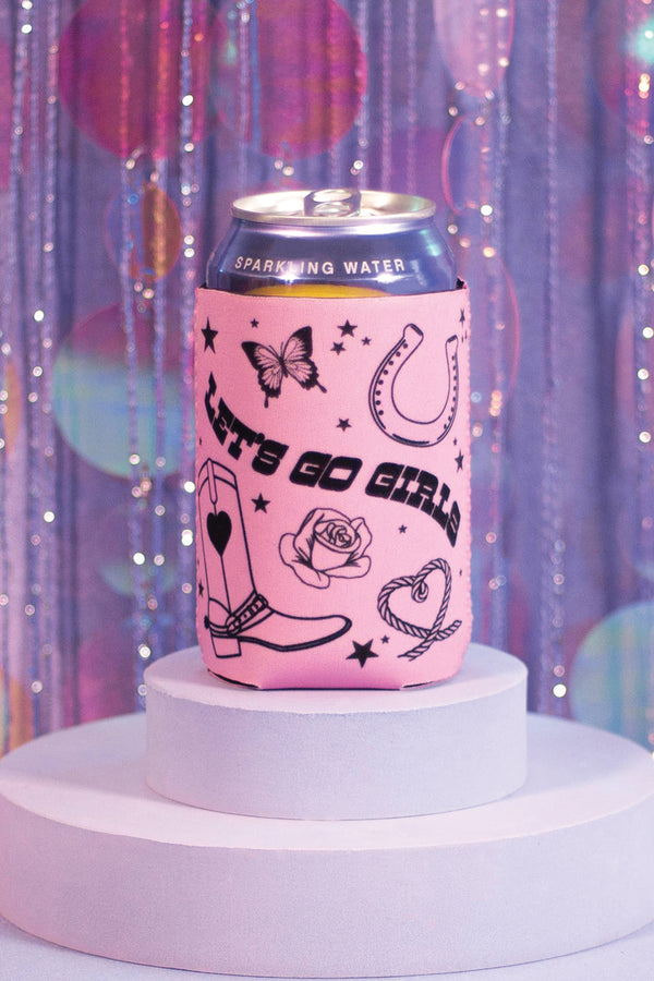 Pink koozie on a white circular platform. The koozie says Lets Go Girls in western font with cowboy boots, roses, ropes, horseshoe, butterfly, and stars surrounding the text. Purple glittery background.