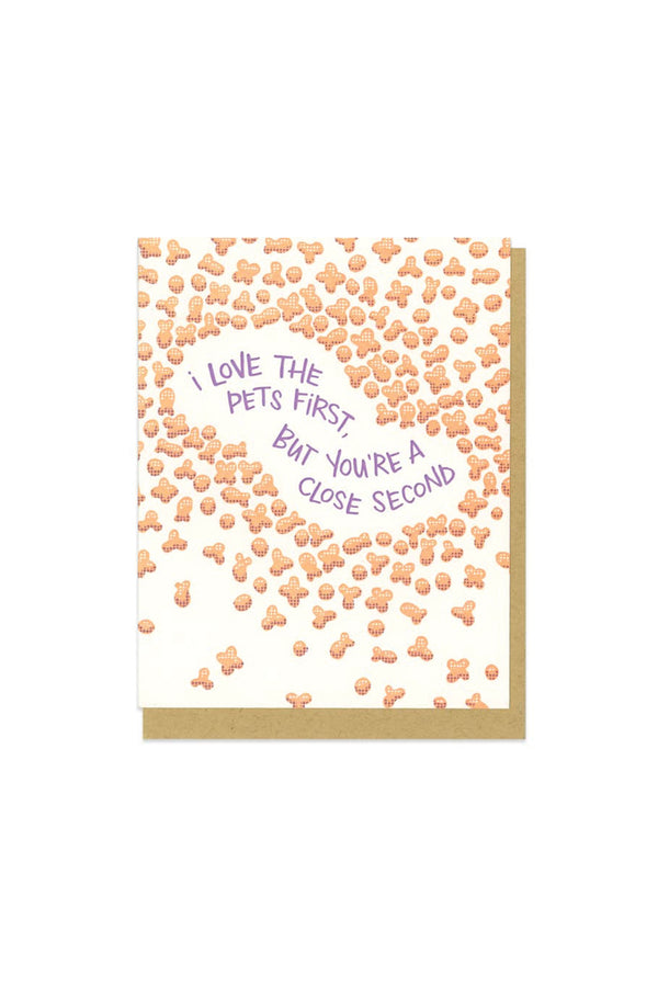 White card on white background. Kraft envelope. The card design is of pet food spread across with purple text in the middle that reads "I love the pets first, but you're a close second."