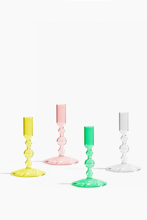 Short yellow, pink, green, and clear glass votive candle holders. White background.
