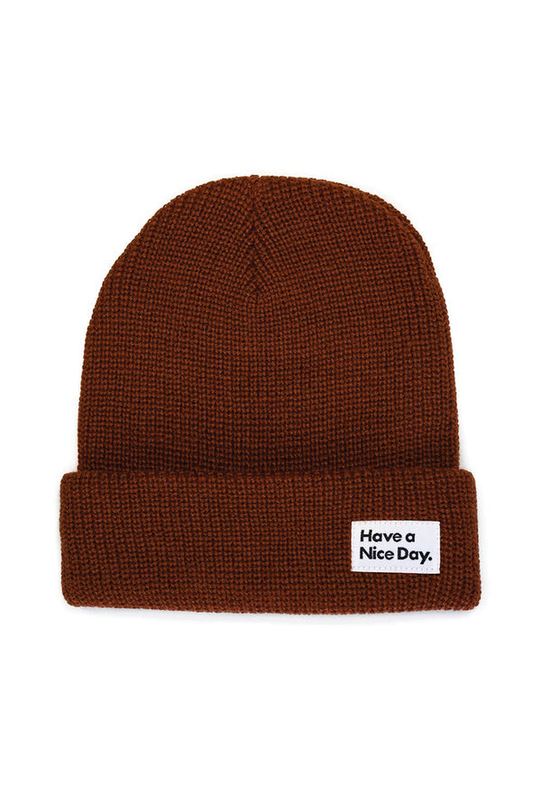 Rust color beanie with white tag on the front that says Have a Nice Day.