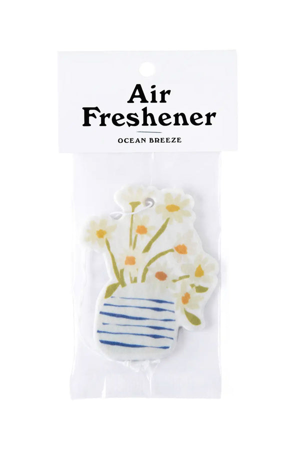 Illustrated air freshener of a blue and white vase filled with daisies. The air freshener has an elastic string and is packed in a clear bag with a white bag topper that says "Air Freshener Ocean Breeze". White background. 