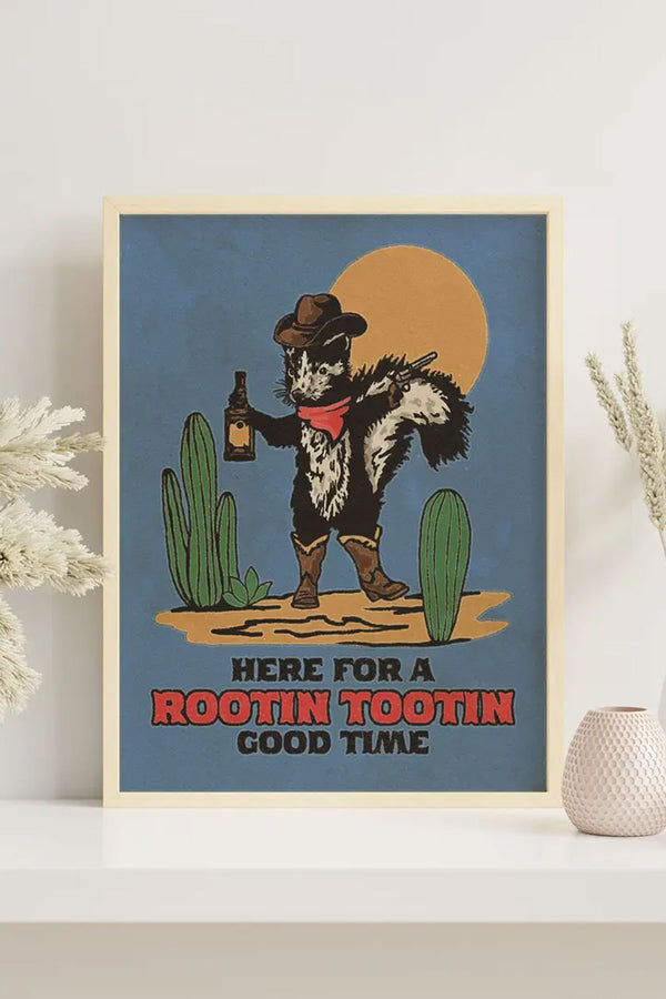 Framed blue poster of a Cowboy Skunk with a cowboy hat, whisky and a pistol. Standing between two cacti. The poster says "Here for a rootin tootin good time" in western text.