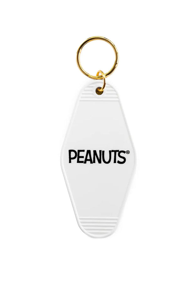 White plastic motel style keyring that says Peanuts. Gold keyching. White background.
