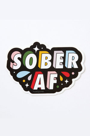 Die cut sticker that says sober AF in block lettering with pink, green, yellow, blue, and red shadows. The background is black and the words are surrounded by random colorful shapes.