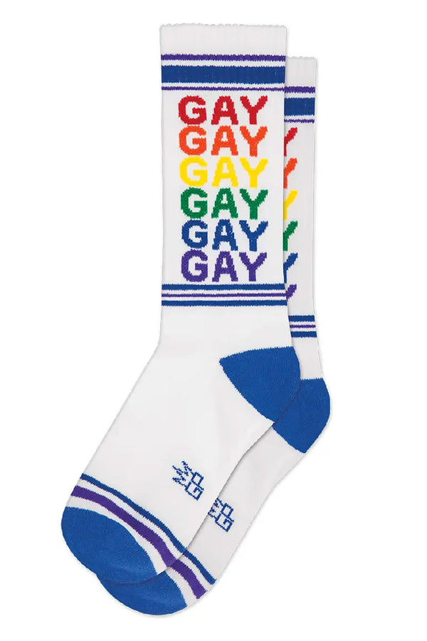 Tall mid calf white crew socks. The socks have blue heels and toes, blue and purple stripes across the toes and around the top of the socks. The Socks say GAY in repeating pattern in rainbow colors. White background.