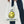 Load image into Gallery viewer, A person in wide leg blue jeans holds white reusable grocery bag from the handles. The bag Says Baggu in black text above a yellow smiley face. Below the smiley face the bag reads &quot;Have a Nice Day!&quot; White background.
