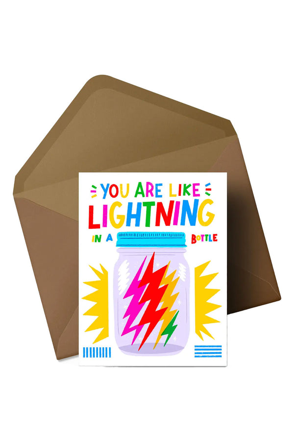 White card says "You are like lightning in a bottle" and features an illustration of a mason jar that contains multicolor lightning bolts. Yellow starbusts behind the illustration. Kraft brown envelope. White Background.